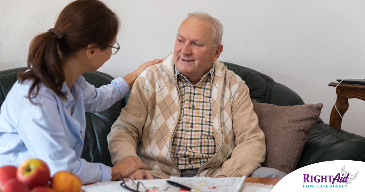 A caregiver compassionately listens to an older man, representing the kind of patience and empathy that help with communicating with clients who have dementia.