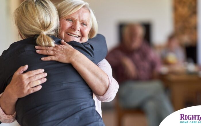 An older woman smiles as a younger woman visits her and hugs her, showing the effect that acts of kindness can have on senior loved ones.