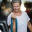 An older woman uses a resistance band to exercise, representing how staying active can help older adults keep their blood pressure in a healthy range.